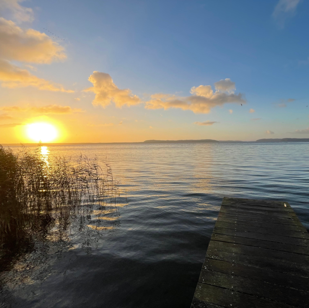 Ein schöner Blick von einem Steg auf das Meer mit Sonnenuntergang am Horizont.