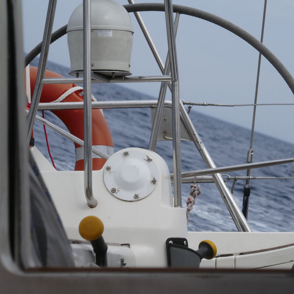 Blick auf einen Steuerstand eines Segelbootes. Im Hintergrund Wasser.