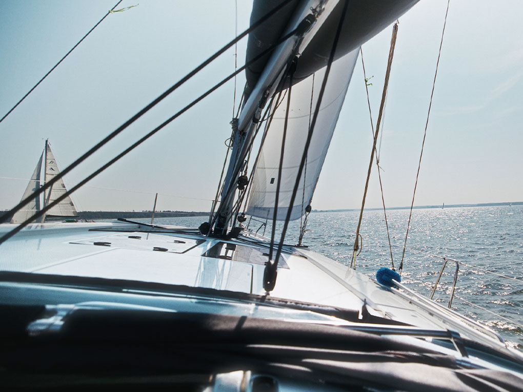 Ausblick von einem Segelboot nach vorn in die Ferne. Im Hintergrund blaues Wasser und ein anderes Segelboot.